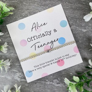 May include: A white card with colorful polka dots and the text "Alice Officially a Teenager" with a silver beaded bracelet with a star charm. The card reads "This little bracelet is just to say have a very special & happy 13th birthday!"