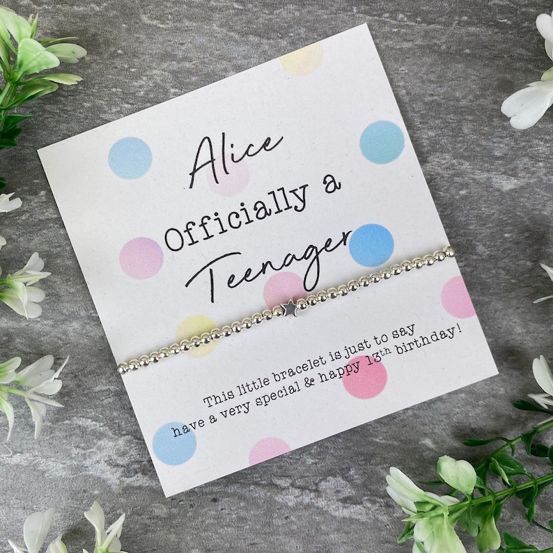 May include: A white card with colorful polka dots and the text "Alice Officially a Teenager" with a silver beaded bracelet with a star charm. The card reads "This little bracelet is just to say have a very special & happy 13th birthday!"