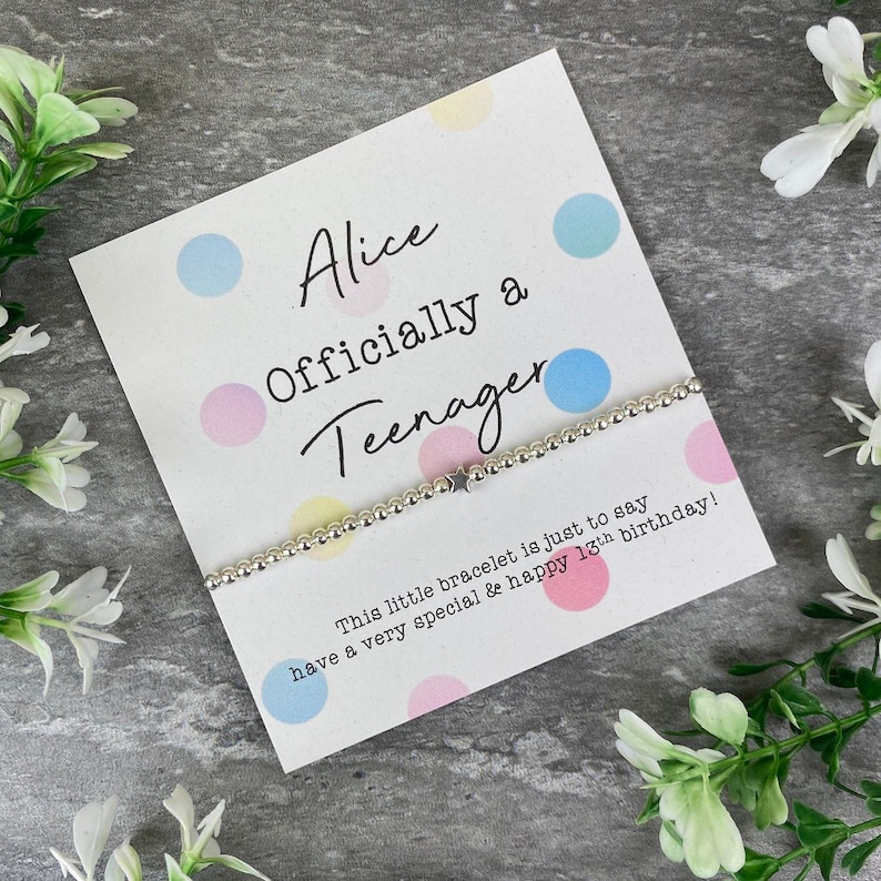 May include: A white card with colorful polka dots reads "Alice Officially a Teenager". A silver bracelet with a star charm is on top of the card. The text below the card reads "This little bracelet is just to say have a very special & happy 13th birthday!"
