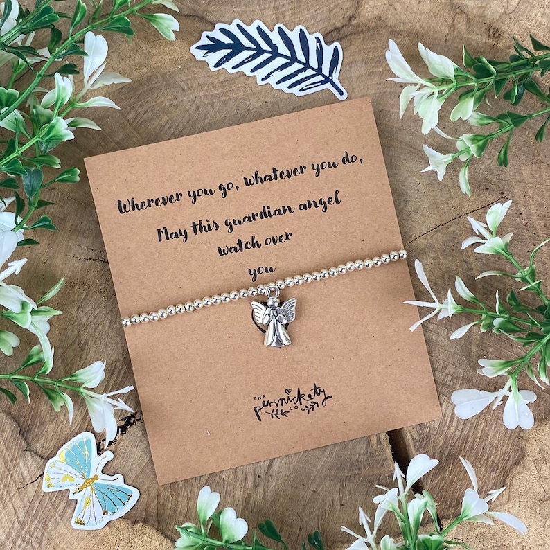 May include: A silver charm bracelet with a guardian angel charm. The bracelet comes with a card that reads "Wherever you go, whatever you do, May this guardian angel watch over you." The card is brown with white text and has a small floral design at the bottom.