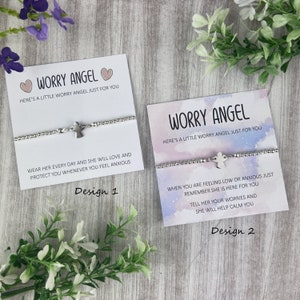 May include: Two cards with the text "Worry Angel" and a silver charm bracelet with a small angel charm. The text on the cards reads "Here's a little worry angel just for you". The first card has the text "Wear her every day and she will love and protect you whenever you feel anxious" and the second card has the text "When you are feeling low or anxious just remember she is here for you. Tell her your worries and she will help calm you". The cards are labelled "Design 1" and "Design 2".
