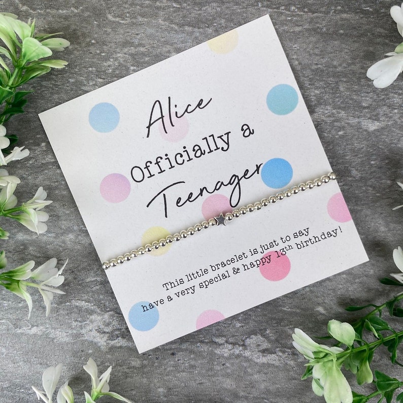 May include: A white card with colorful polka dots and the text "Alice Officially a Teenager". A silver bracelet with a star charm is on the card. The text on the card reads "This little bracelet is just to say have a very special & happy 13th birthday!"