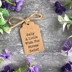 May include: A brown paper gift tag with a twine bow. The tag has the text "Sally A Little Wish For Stress Relief" printed on it.