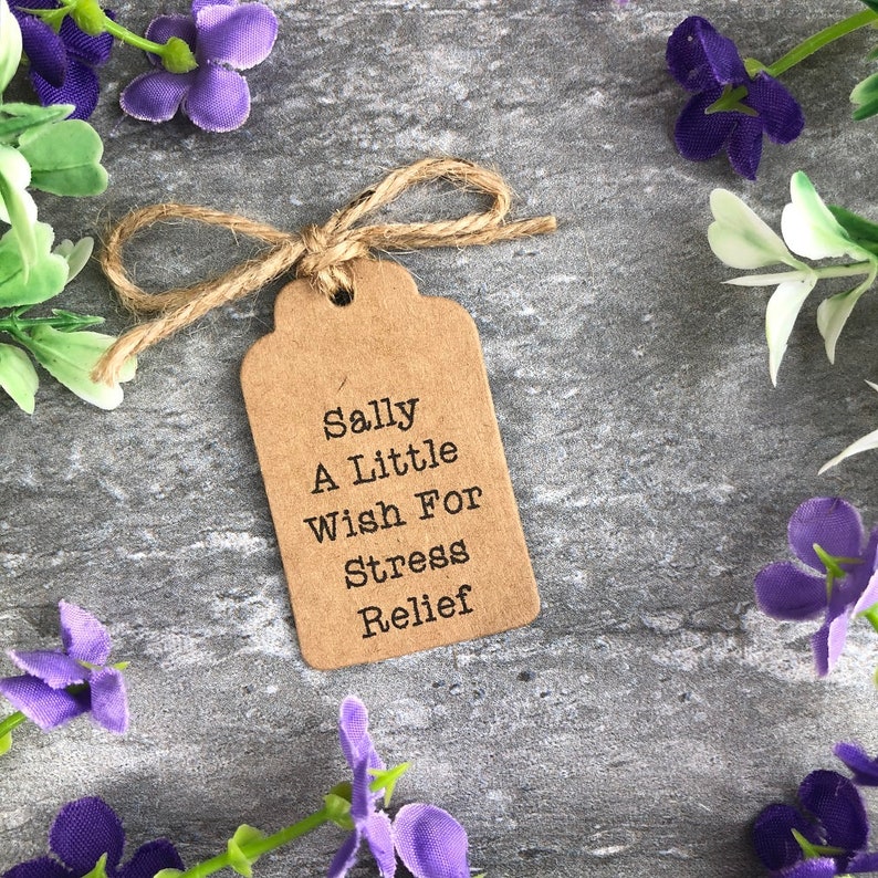 May include: A brown paper gift tag with a twine bow. The tag has the text "Sally A Little Wish For Stress Relief" printed on it.