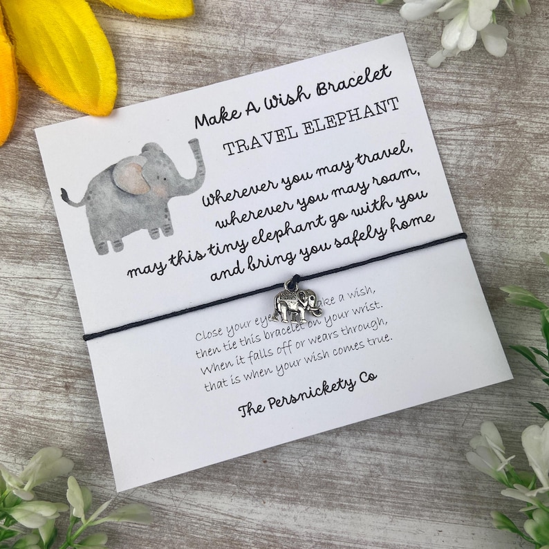 May include: A black string bracelet with a silver elephant charm. The card attached to the bracelet reads "Make A Wish Bracelet Travel Elephant" and includes a message about making a wish when the bracelet falls off.