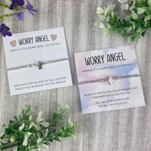 May include: Two silver bracelets with angel charms and inspirational messages. The bracelets are on white cards with pink hearts and a watercolour background. The text on the cards reads "Worry Angel" and "Here's a little worry angel just for you".