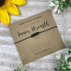 May include: Black wish bracelet with black onyx beads and a kraft paper card that reads "Make A Wish Bracelet A Little Wish For Inner Strength Onyx Close your eyes and make a wish then tie this bracelet on your wrist. When it falls off or wears through, that is when your wish comes true. The Persnickety Co"