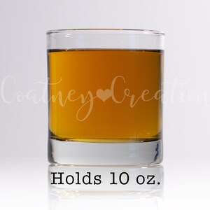 May include: A clear glass tumbler with a brown liquid inside. The glass has the text "Holds 10 oz." printed on the bottom.
