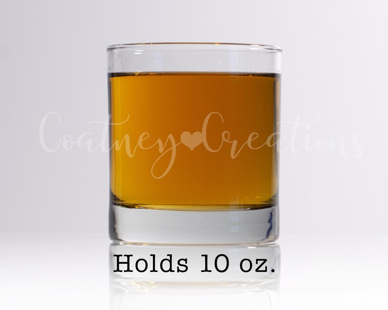 May include: A clear glass tumbler with a brown liquid inside. The glass has the text "Holds 10 oz." printed on the bottom.