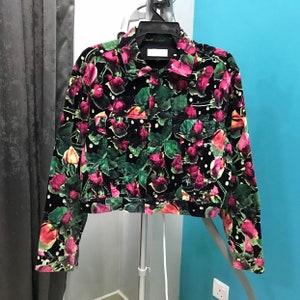 May include: A black velvet jacket with a floral print of pink and green roses. The jacket has a button-up front and long sleeves.