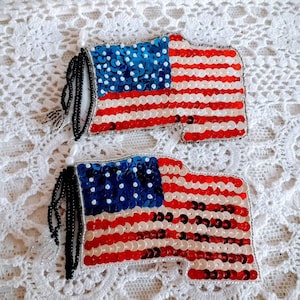 以下が含まれることがあります： 黒いビーズのフリンジが付いた、スパンコールのアメリカ国旗のパッチが2つ。旗は赤、白、青です。