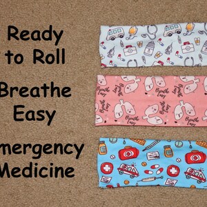May include: Three headbands with different medical-themed prints. The top headband is light blue with a white ambulance, stethoscope, pills, and other medical symbols. The middle headband is pink with white lungs and the text "Breathe Easy". The bottom headband is light blue with a white ambulance, pills, and a red cross.