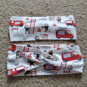 May include: Two white fabric headbands with a red, white, and blue fire truck and firefighter pattern.