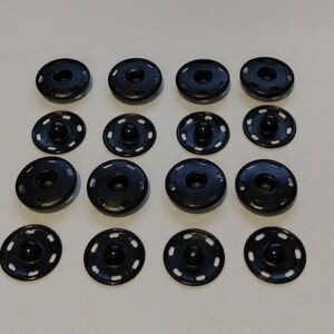 May include: A set of 15 black snap buttons, each with a raised center and a decorative ring around the edge.