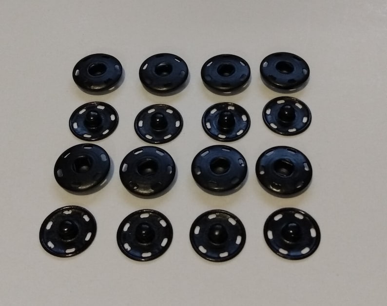 May include: A set of 15 black snap buttons, each with a raised center and a decorative ring around the edge.