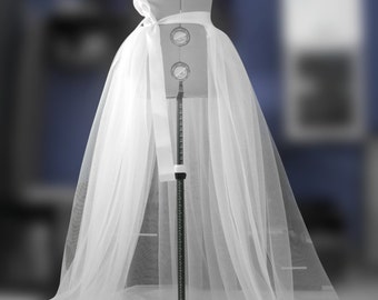 Puede incluir: Una falda de tul blanco con una cinta de satén blanco atada alrededor de la cintura. La falda se muestra en un maniquí contra un fondo azul. El texto "By Asya Kolarova MADE TO MEASURE" se muestra sobre la falda.