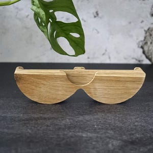 May include: A wooden, semi-circular shelf with a curved design. The shelf is made of light-colored wood and has a natural finish. The shelf is designed to hold small items and has a unique, modern look.