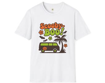 May include: White t-shirt with a colourful graphic. The design features the words "Scooby Boo!" in orange and green, a brown van with a pumpkin, bats, flowers, and a palm tree. A fun Halloween-themed tee.