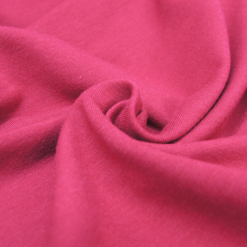 Puede incluir: Primer plano de una tela suave de color rojo con una textura lisa. La tela est&aacute; doblada y drapeada, creando un aspecto fluido y elegante.