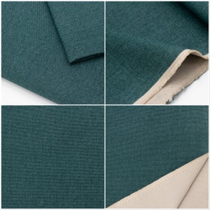 May include: Close-up of a dark teal fabric with a subtle textured weave. The fabric is folded in several places, showing the raw edge and the underside of the fabric, which is a light beige colour.