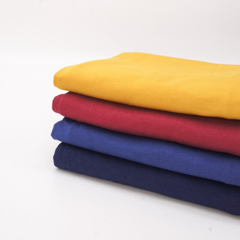 May include: Four fabric swatches stacked on top of each other. The top swatch is yellow, the second is red, the third is blue, and the bottom swatch is dark blue.