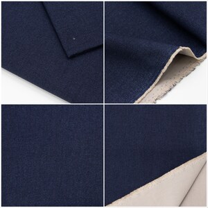 May include: Close-up of a dark blue fabric with a subtle texture. The fabric is folded in half, revealing a lighter beige lining.
