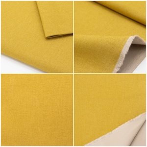 May include: Close-up of a yellow fabric with a textured weave. The fabric is folded in half, showing the underside of the fabric, which is a light beige colour.