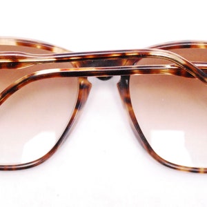May include: Tortoiseshell eyeglasses with gold accents and the word "NEO" on each arm.