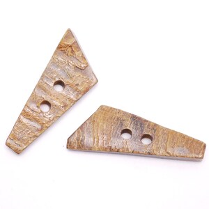 May include: Two brown, triangular shaped buttons with two holes each. The buttons are made of a natural material with a textured surface.