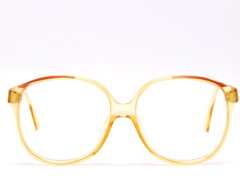 May include: A pair of round, amber-colored eyeglasses with a brown trim. The glasses have a classic, retro style.