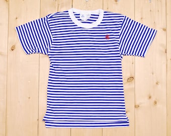 Puede incluir: Una camiseta de manga corta a rayas azules y blancas con un pequeño logotipo rojo en el pecho.