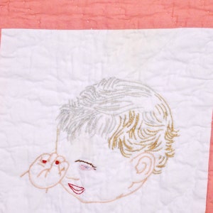 May include: Embroidered image of a child's face on a white background with a pink border. The child has blonde hair and is looking to the side. The child's hand is raised to their face.