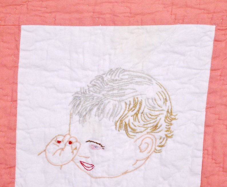 May include: Embroidered image of a child's face on a white background with a pink border. The child has blonde hair and is looking to the side. The child's hand is raised to their face.