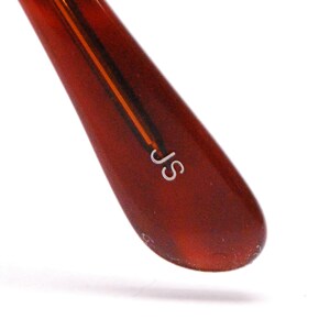 May include: Close-up of a brown tortoiseshell glasses arm with the letters "JS" engraved in white.
