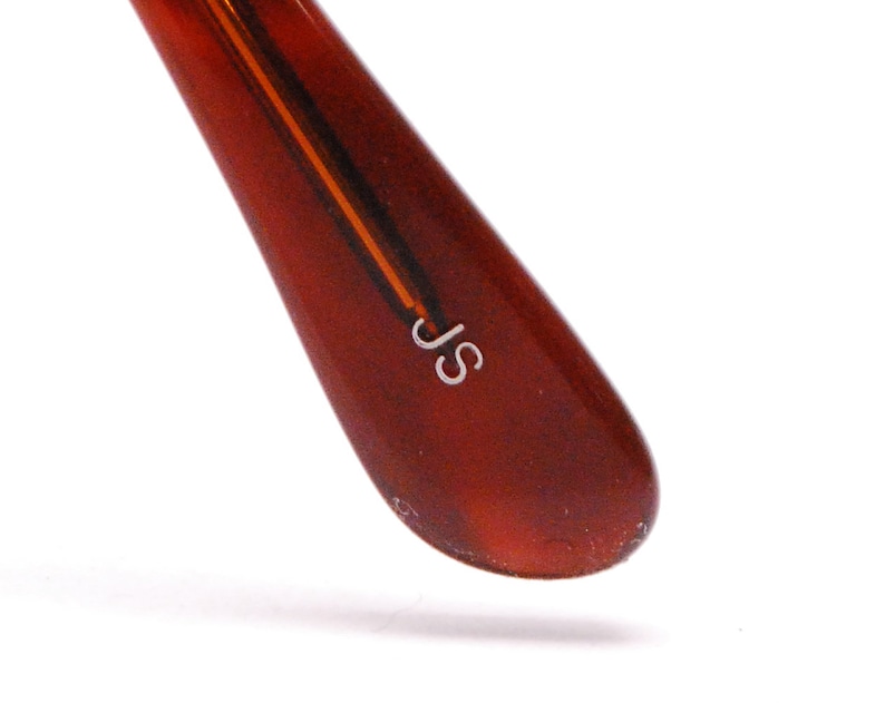 May include: Close-up of a brown tortoiseshell glasses arm with the letters "JS" engraved in white.