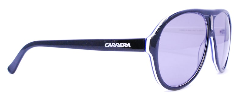 Puede incluir: Gafas de sol aviador negras con un detalle de banda blanca y azul en el marco. Las gafas de sol llevan el logotipo de Carrera en el marco.