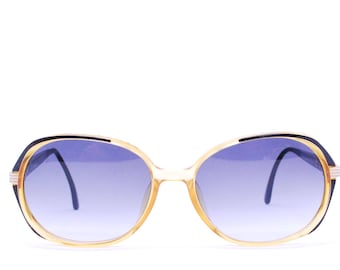 May include: A pair of oval-shaped sunglasses with a gold frame and blue tinted lenses.