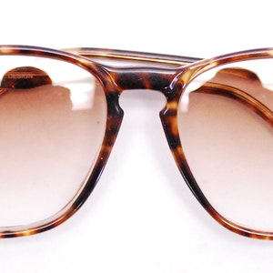 May include: Tortoiseshell eyeglasses with brown tinted lenses.