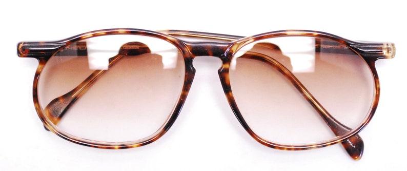 May include: Tortoiseshell eyeglasses with brown tinted lenses.