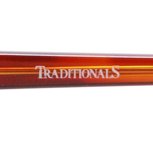 May include: Close-up of the brown tortoise shell temple arm of a pair of eyeglasses with the word "TRADITIONALS" printed in white.