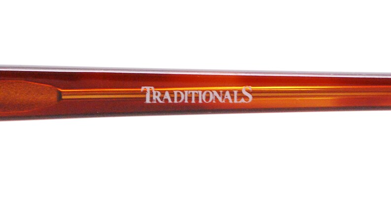 May include: Close-up of the brown tortoise shell temple arm of a pair of eyeglasses with the word "TRADITIONALS" printed in white.