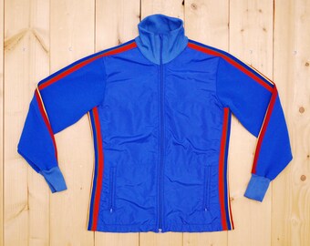 May include: A blue vintage track jacket with a zipper closure and colorful stripes down the sleeves and sides. The jacket has a high collar and a slightly textured fabric.