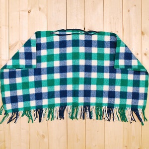 May include: A green, white, and blue plaid throw blanket with fringe on the bottom edge.