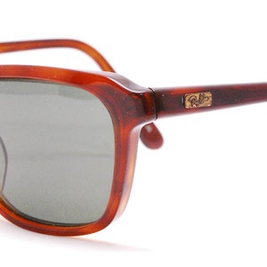 May include: Brown tortoise shell frame sunglasses with green lenses and gold Ray-Ban branding on the right temple.