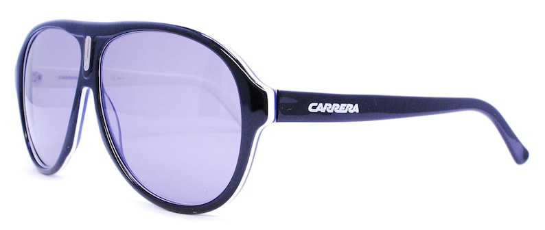 Puede incluir: Gafas de sol aviador negras con una franja blanca en el marco y la palabra "CARRERA" impresa en el lateral.