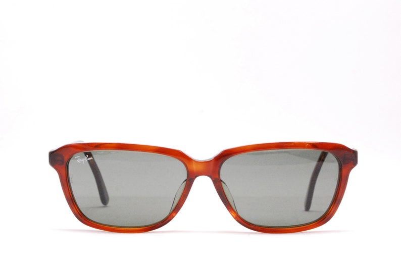 May include: A pair of brown tortoise shell Ray-Ban sunglasses with gray lenses.