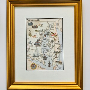 May include: A framed illustration of the Chesapeake Bay, Maryland, with a detailed map of the bay and surrounding areas. The illustration includes various landmarks, including lighthouses, boats, and the state flag of Maryland. The title "The Chesapeake Bay" is printed at the top of the illustration.