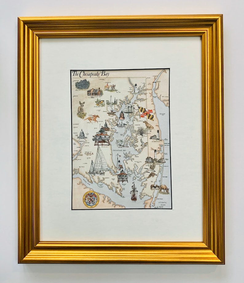 May include: A framed illustration of the Chesapeake Bay, Maryland, with a detailed map of the bay and surrounding areas. The illustration includes various landmarks, including lighthouses, boats, and the state flag of Maryland. The title "The Chesapeake Bay" is printed at the top of the illustration.