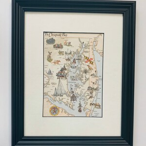 May include: A framed illustration of the Chesapeake Bay, Maryland, with a detailed map of the bay and surrounding areas. The illustration includes various landmarks, including the Chesapeake Bay Bridge, the US Naval Academy, and the Baltimore Inner Harbor. The title "The Chesapeake Bay" is written at the top of the illustration.