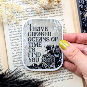 May include: A black and white sticker with a floral design and the text "I have crossed oceans of time to find you".